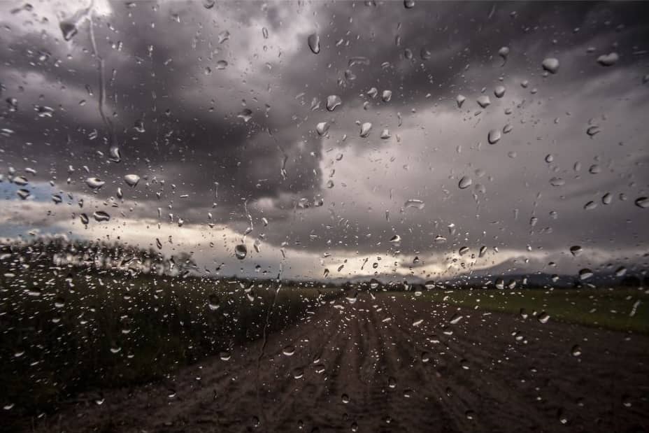Rain falling on a dirt road from dark clouds.