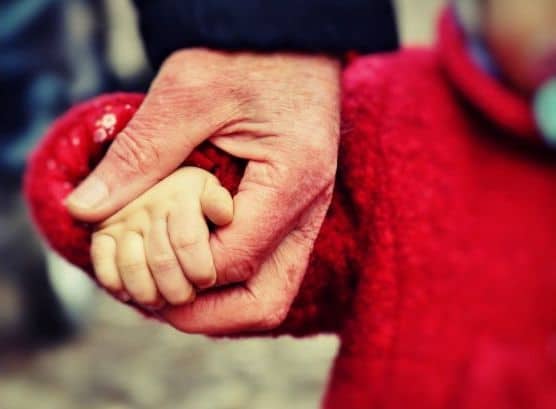 A parent holding his child's hand to cross a street.