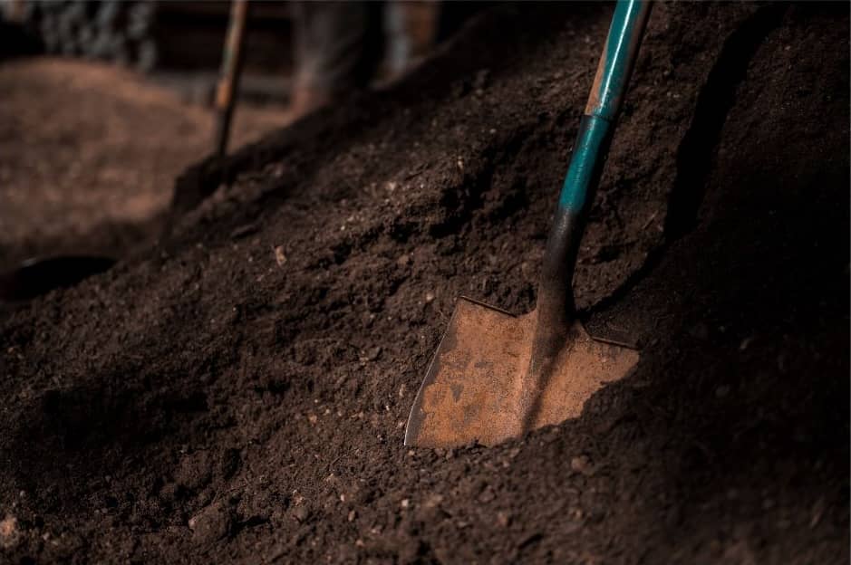 A green shovel sticking into a pile of dirt.
