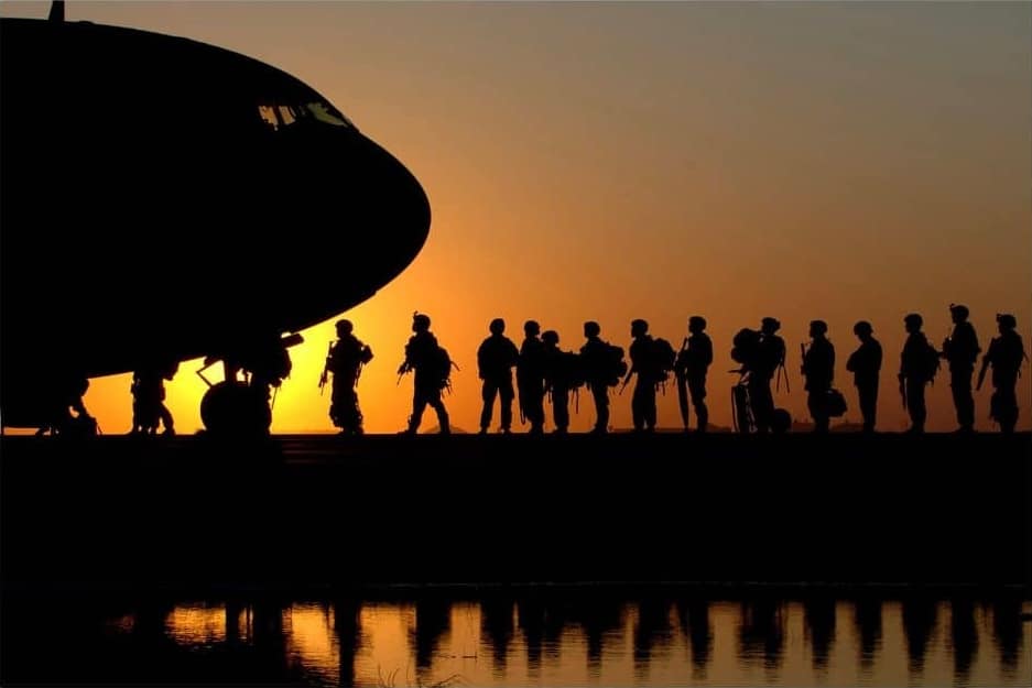 Soldiers boarding a transport plane at sunset.